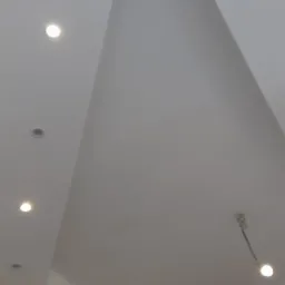 Nowoczesny biały sufit z wbudowanymi punktowymi światłami LED i dekoracyjnym podwieszanym elementem w kształcie trapezu.