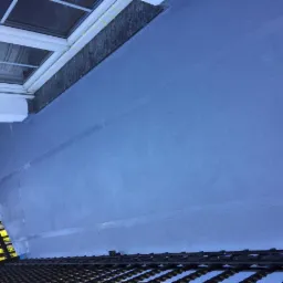 Szary, świeżo wylany balkon z widoczną balustradą i oknem z białymi ramami w tle.