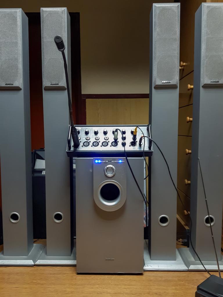 Zestaw głośników kina domowego marki Xenon z subwooferem, kolumnami podłogowymi i mikserem audio, ustawiony na drewnianej podłodze.