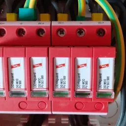 Rozdzielnica z modułami DEHNguard DG MOD PV SCI 500, zabezpieczającymi instalację fotowoltaiczną przed przepięciami, widoczne przewody zasilające i uziemiające.