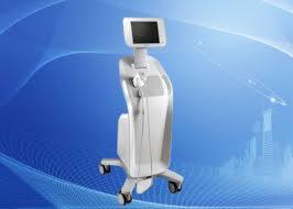 Biały, nowoczesny sprzęt kosmetyczny na kółkach z ekranem dotykowym na tle abstrakcyjnej grafiki w odcieniach niebieskiego.