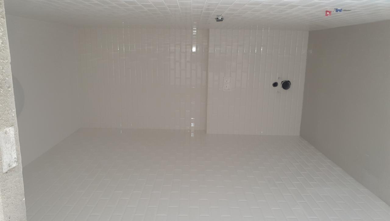 Wykończone wnętrze łazienki z białymi, błyszczącymi płytkami ułożonymi w cegiełkę na ścianach i podłodze, widoczne wyprowadzenia hydrauliczne i elektryczne.