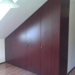 db BEAUTY - Wbudowana szafa z ciemnego drewna, dopasowana do skosu poddasza, z małymi, metalowymi uchwytami na drzwiach.