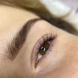 Zbliżenie na oko z przedłużonymi rzęsami i brwią po zabiegu w Sosnowcu, widoczne delikatne światło odbijające się w źrenicy.