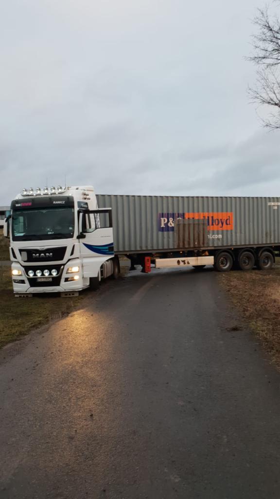 Ciężarówka MAN z otwartymi drzwiami kabiny, ciągnąca kontener P&O Lloyd na asfaltowej drodze w pochmurny dzień.