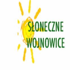 Logo firmy deweloperskiej 'Słoneczne Wojnowice' z motywem słońca w tle, zielony napis na białym tle.
