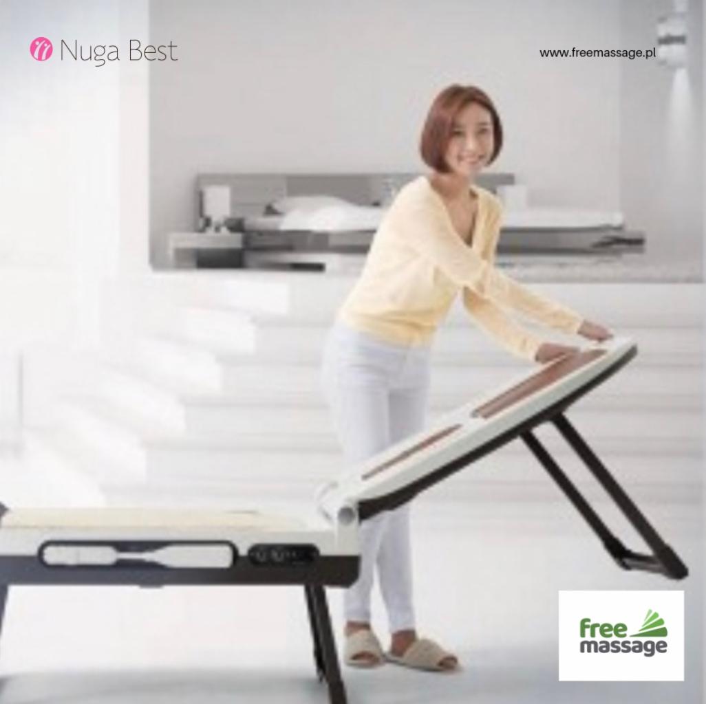 Kobieta w jasnych ubraniach demonstruje działanie automatycznego łóżka masującego z panelami sterującymi, widoczne logo 'Nuga Best' i adres strony internetowej.