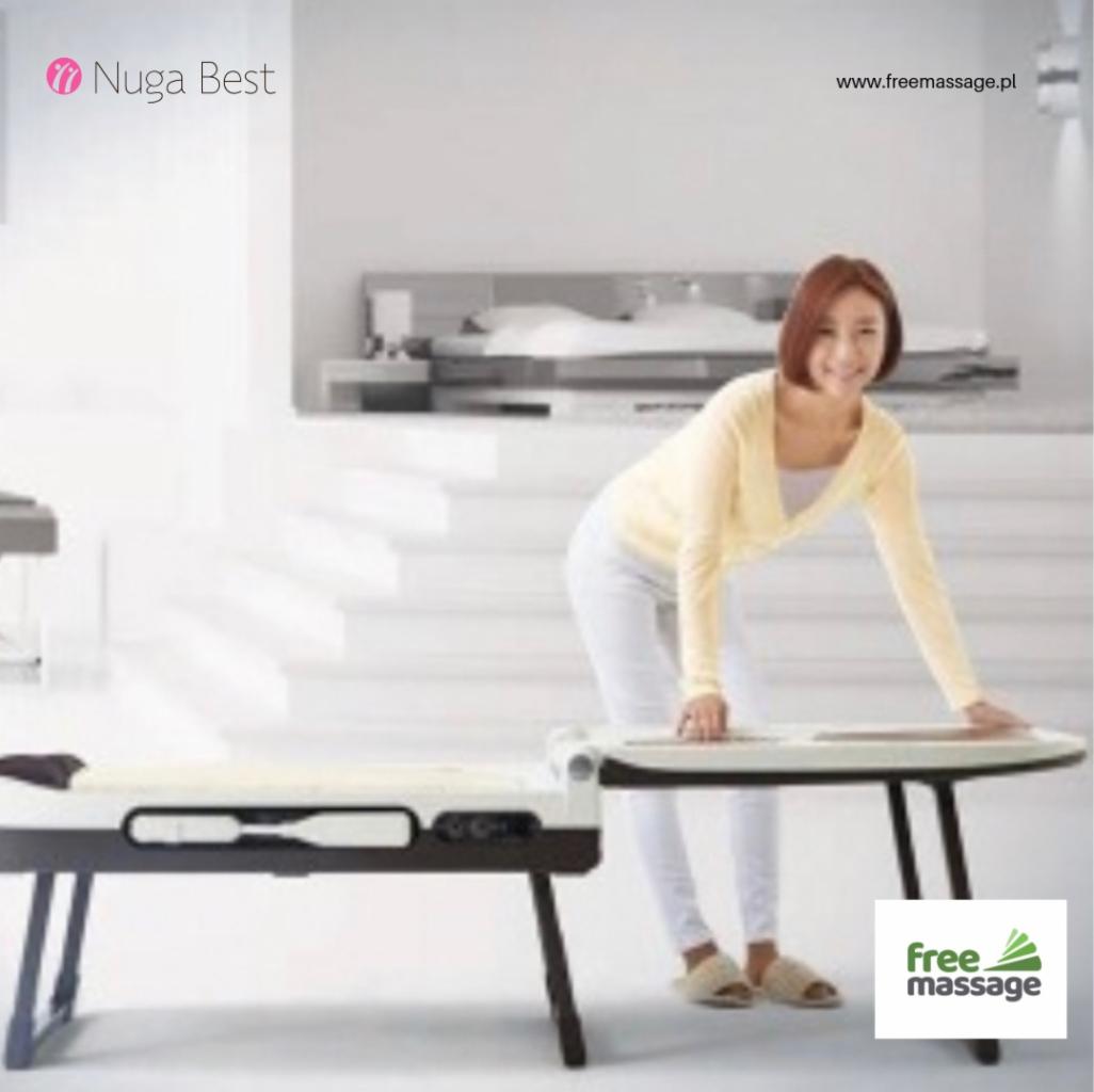 Uśmiechnięta kobieta w jasnej bluzce przygotowuje automatyczne łóżko do masażu Nuga Best w jasnym wnętrzu.