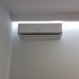 KLIMAR - Biały klimatyzator marki Gree zamontowany na białej ścianie pod sufitem z wbudowanym oświetleniem LED.