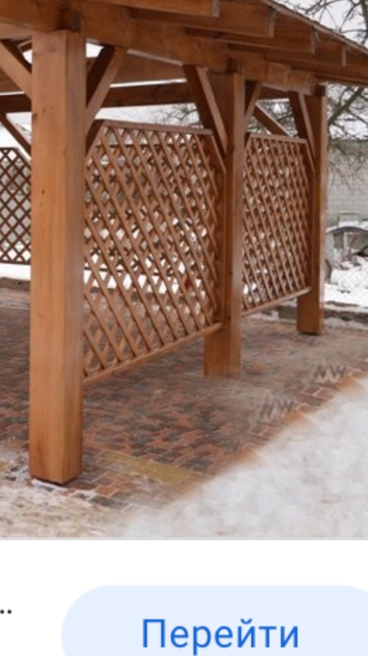 Zadaszona drewniana altana z kratowanymi ścianami, postawiona na brukowanej powierzchni na zewnątrz w chłodny dzień.