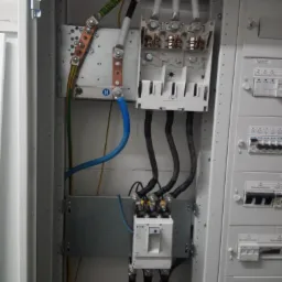 Rozdzielnica elektryczna z widocznymi przewodami, bezpiecznikami i szynami montażowymi, zrealizowana instalacja elektryczna we Wrocławiu.