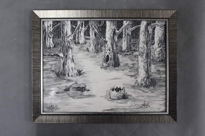 Czarno-biały szkic lasu w srebrnej ramie, przedstawiający drzewa z wyraźnymi teksturami kory i dwa pniaki na pierwszym planie.