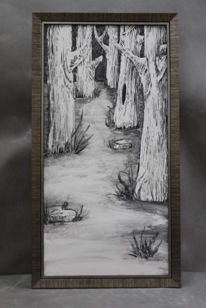 Czarno-biały obraz w ramie przedstawiający leśną ścieżkę z wysokimi drzewami i kępami trawy, wykonany w technice przypominającej rysunek węglem lub ołówkiem.