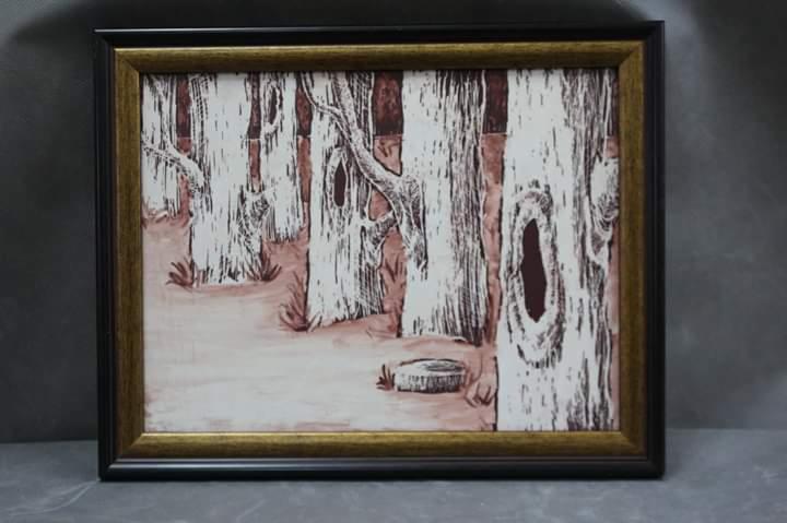 Oprawiony obraz przedstawiający stylizowany las z białymi drzewami i brązowymi akcentami, widoczny pień drzewa na pierwszym planie, całość w czarno-złotej ramie.