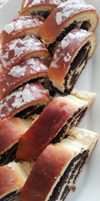 Kawałki makowca z lukrem, ułożone na białym talerzu, widoczne warstwy ciasta i nadzienia makowego.