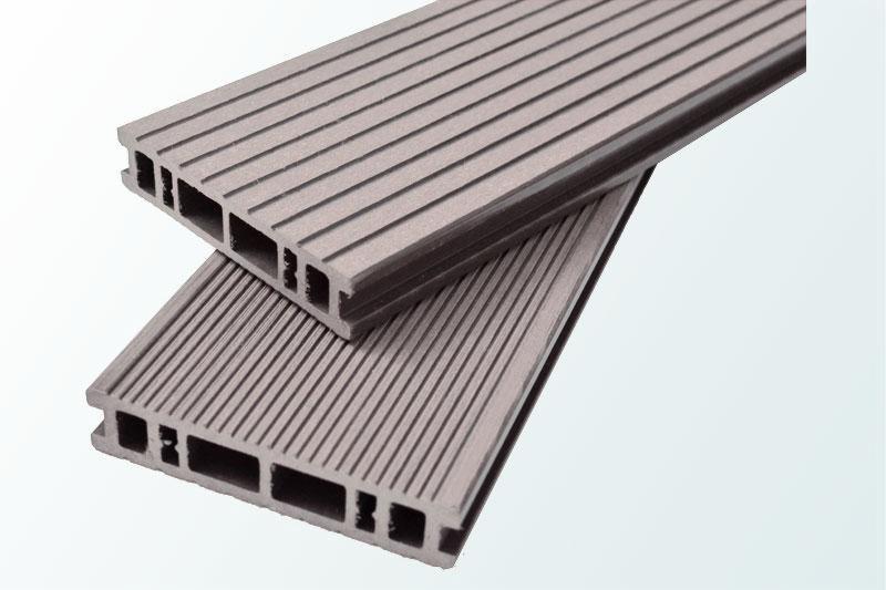 Dwie deski kompozytowe ryflowane, w kolorze szarym, z widocznym przekrojem wewnętrznym z pustymi przestrzeniami, ułożone jedna na drugiej.