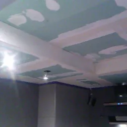 Kuchenny sufit z płyt kartonowo-gipsowych w trakcie szpachlowania, widoczne łączenia płyt i wstępne warstwy gładzi, zarys instalacji oświetleniowej.