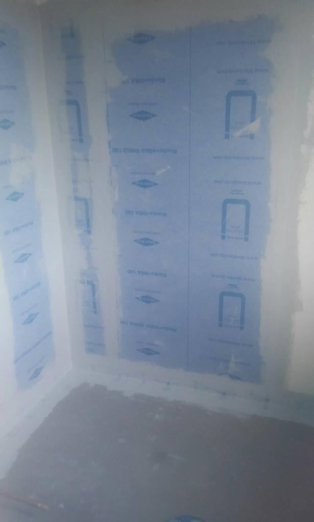 Przygotowanie ścian w łazience do położenia płytek, zabezpieczone niebieską folią hydroizolacyjną Blanke Aqua Shield 100, widoczne łączenia zabezpieczone taśmą.