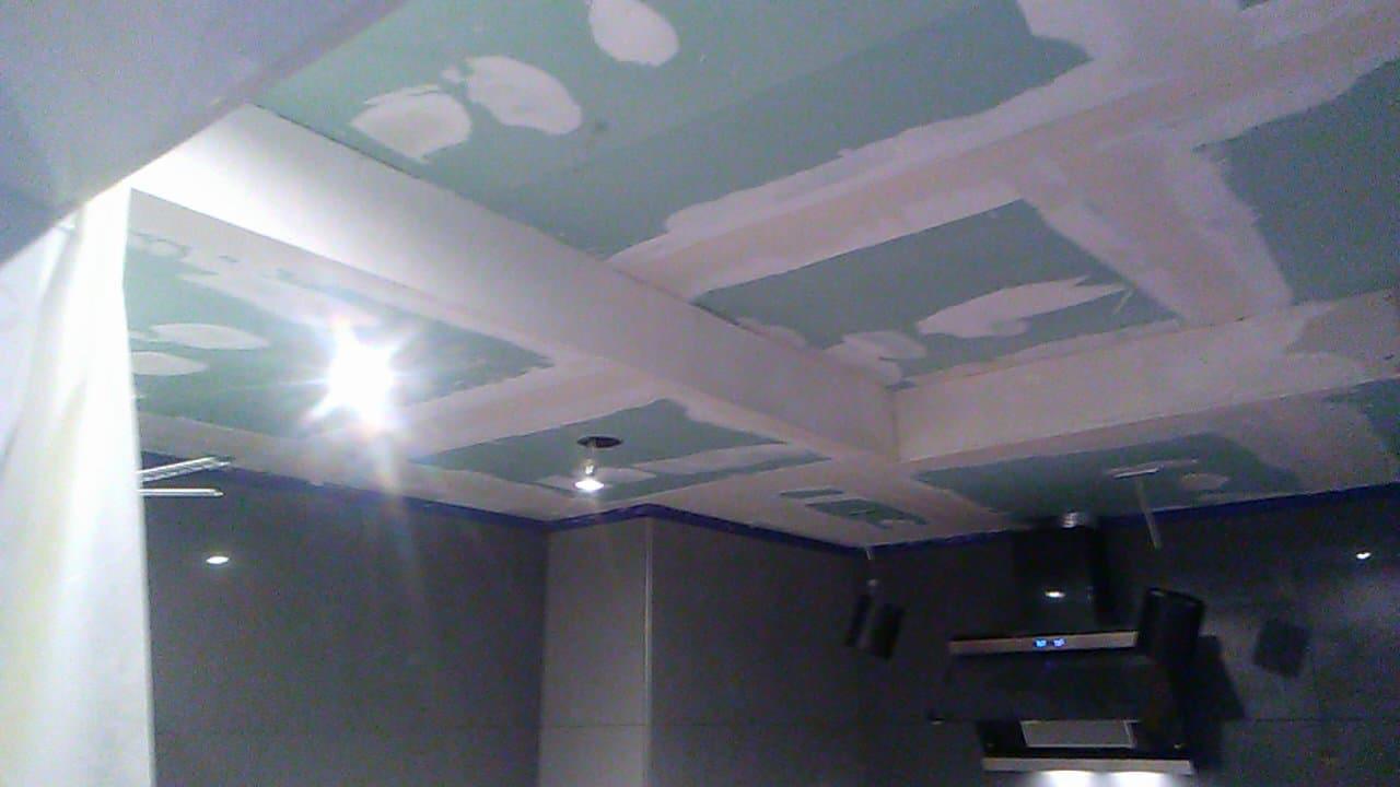 Kuchenny sufit z płyt kartonowo-gipsowych w trakcie szpachlowania, widoczne łączenia płyt i wstępne warstwy gładzi, zarys instalacji oświetleniowej.