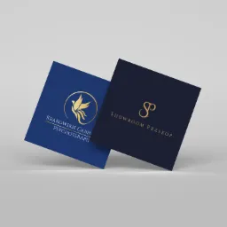 Dwie wizytówki z eleganckim, złotym logo na granatowym tle, jedna z logo ptaka w okręgu dla 'Krakowskie Gabinety Psychoterapii', druga z inicjałami 'SP' dla 'Showroom Przekop'.