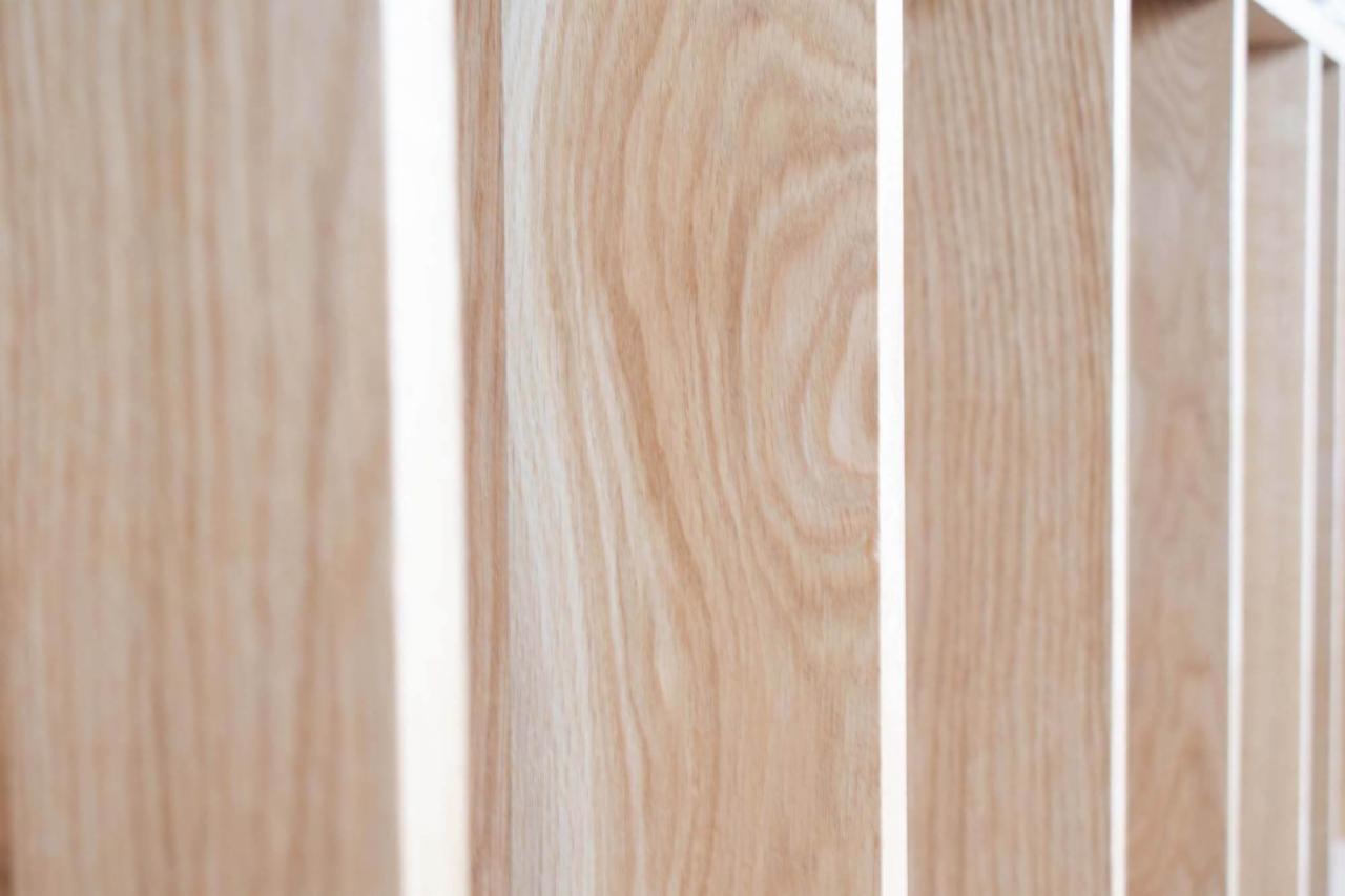 Szczegółowe ujęcie drewnianej balustrady schodów z jasnego drewna, ukazujące naturalny rysunek słojów i precyzyjne wykończenie.