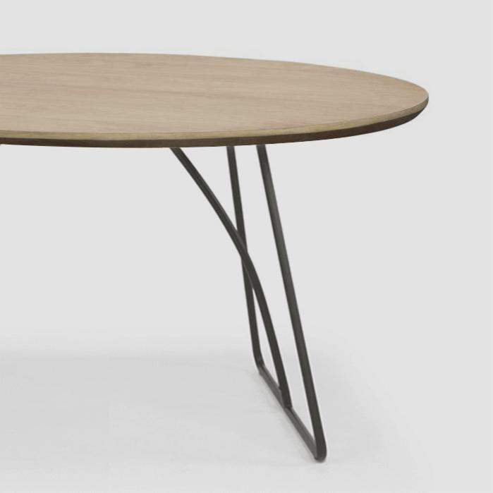 Okrągły blat drewniany na czarnych metalowych nogach w minimalistycznym stylu, widok z boku.