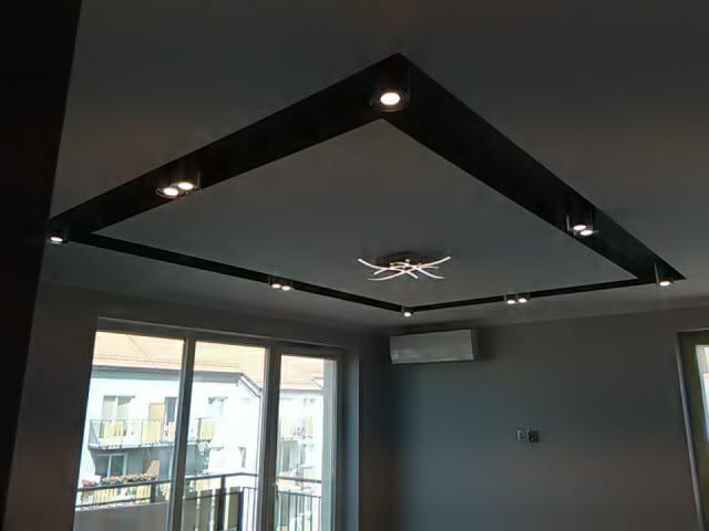 Nowoczesny sufit podwieszany z czarną ramą i punktowym oświetleniem LED, centralna lampa ozdobna w kształcie gwiazdy, klimatyzator na ścianie w tle