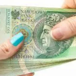 Dłoń z turkusowym paznokciem trzyma plik banknotów 100 zł na białym tle.