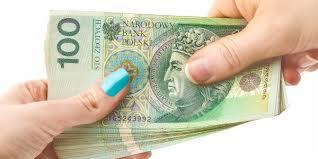 Dłoń z turkusowym paznokciem trzyma plik banknotów 100 zł na białym tle.