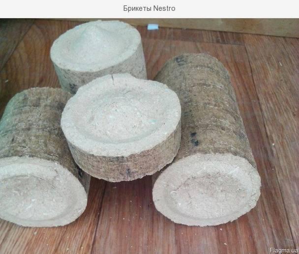 Cztery okrągłe i walcowate brykiety Nestro ułożone na drewnianej podłodze, widoczne ślady po prasowaniu.
