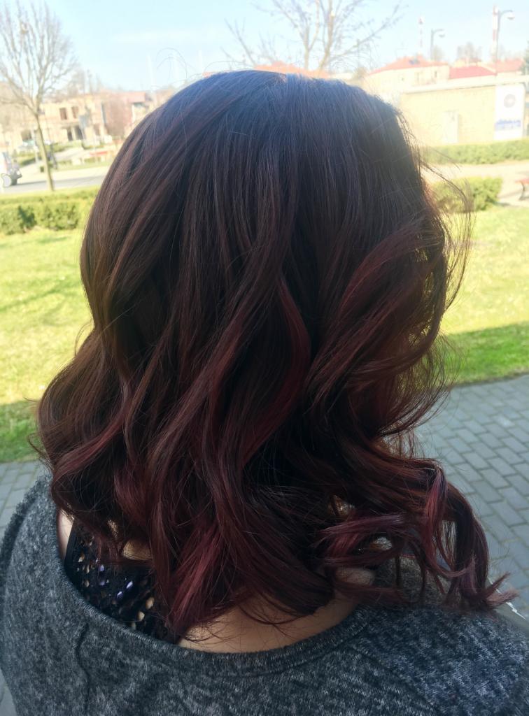 Ciemne, falowane włosy z bordowymi refleksami, widok z tyłu na tle parku.