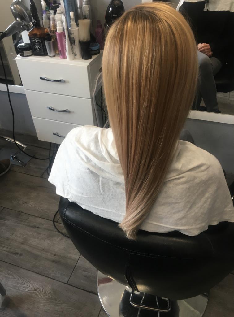 Proste, blond włosy z ombre, widok z tyłu na fotelu w salonie, biała peleryna ochronna.