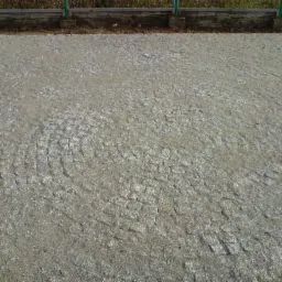 Ułożona nawierzchnia z szarej kostki w radialny wzór, widoczne zakończenie obrzeża.