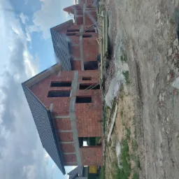 Wznoszone domy z czerwonej cegły z częściowo położonym dachem z dach&oacute;wki ceramicznej, widoczne z perspektywy ziemi w pochmurny dzień.