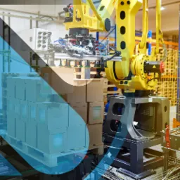 Ż&oacute;łty robot przemysłowy przenosi kartony na palecie w magazynie, widoczne suwnice i regały.