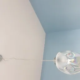 Ściana i sufit pomalowane na biało i błękitno z zamontowaną lampą z opalizującego szkła.