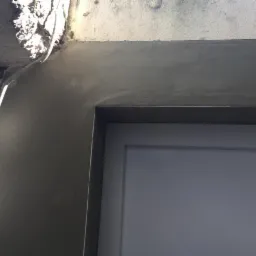 Wykończenie ościeżnicy drzwiowej w Ostrowie Wielkopolskim, z widocznymi śladami świeżo nałożonego tynku i instalacją elektryczną w tle.