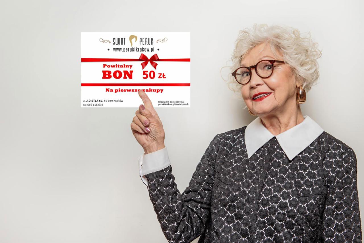 Uśmiechnięta starsza kobieta w okularach prezentuje bon o wartości 50 zł na pierwszy zakup w salonie peruk Świat Peruk, wskazując na niego palcem.