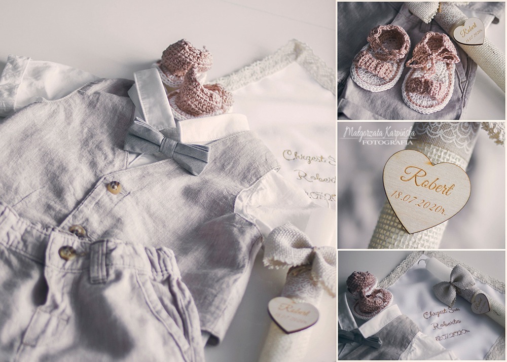 Kompozycja ubranek chłopięcych, dzierganych bucików, świecy i haftowanego kocyka z imieniem Robert na chrzest, w stonowanej kolorystyce.