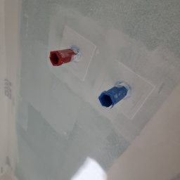 Usługi Budowlane Łukasz Jaromieńczuk - Przygotowane podejścia instalacyjne, rura czerwona i niebieska, wystające ze ściany z płyt kartonowo-gipsowych, zabezpieczone białym silikonem, przed położeniem płytek w łazience.