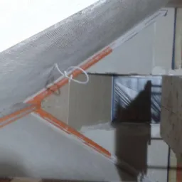 Skośne poddasze w trakcie ocieplania, widoczne pomarańczowe profile, siatka z włókna szklanego i folia ochronna na podłodze.