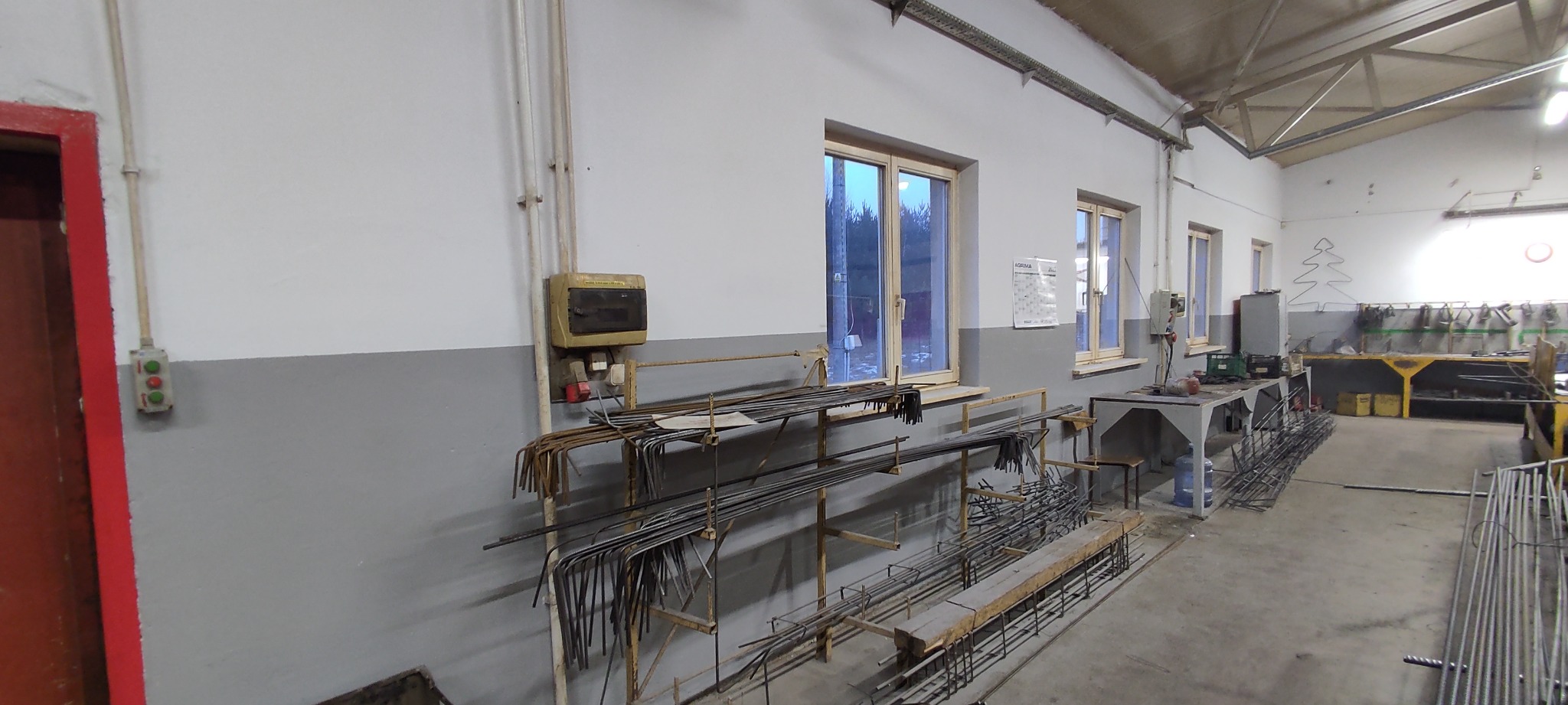 Warsztat w Chęcinach z zapasem prętów zbrojeniowych na regałach i stołach, przygotowanych do dalszej obróbki.