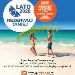 Para w strojach kąpielowych spaceruje po piaszczystej plaży, chroniąc się przed słońcem pod dużym liściem palmy; w tle turkusowe morze i reklama salonu podróży z ofertą 'Lato 2020' i rabatami.