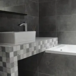 Nowoczesna łazienka z umywalką nablatową i wanną, wykończona szarą płytką wielkoformatową i mozaiką w odcieniach szarości.