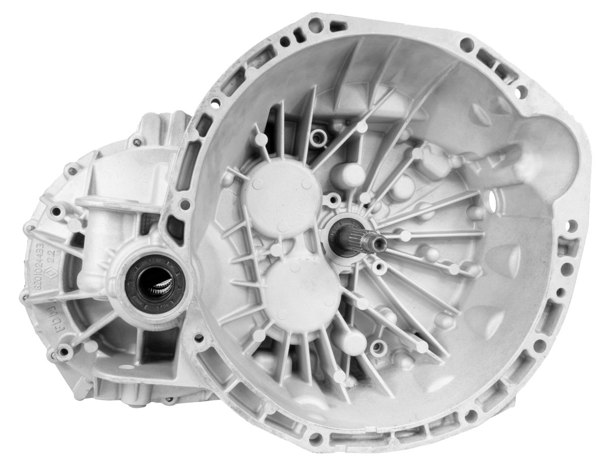 Otwarta, aluminiowa obudowa skrzyni biegów z widocznymi elementami wewnętrznymi i wałkiem wejściowym, oświetlona neutralnym światłem.