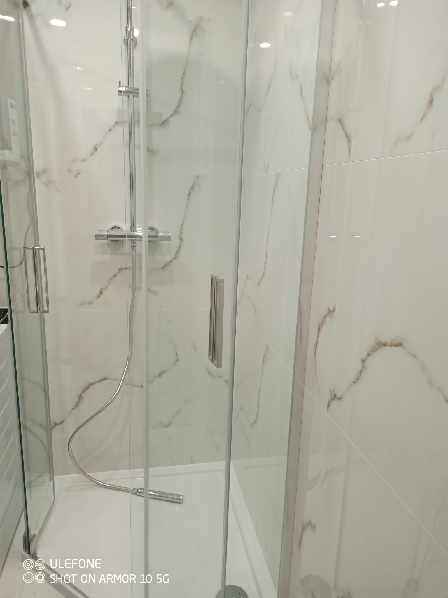 Kabina prysznicowa z marmurowymi płytkami w Goleszowie. Chromowana armatura, szklane drzwi z uchwytami. Nowoczesny design łazienki po remoncie.