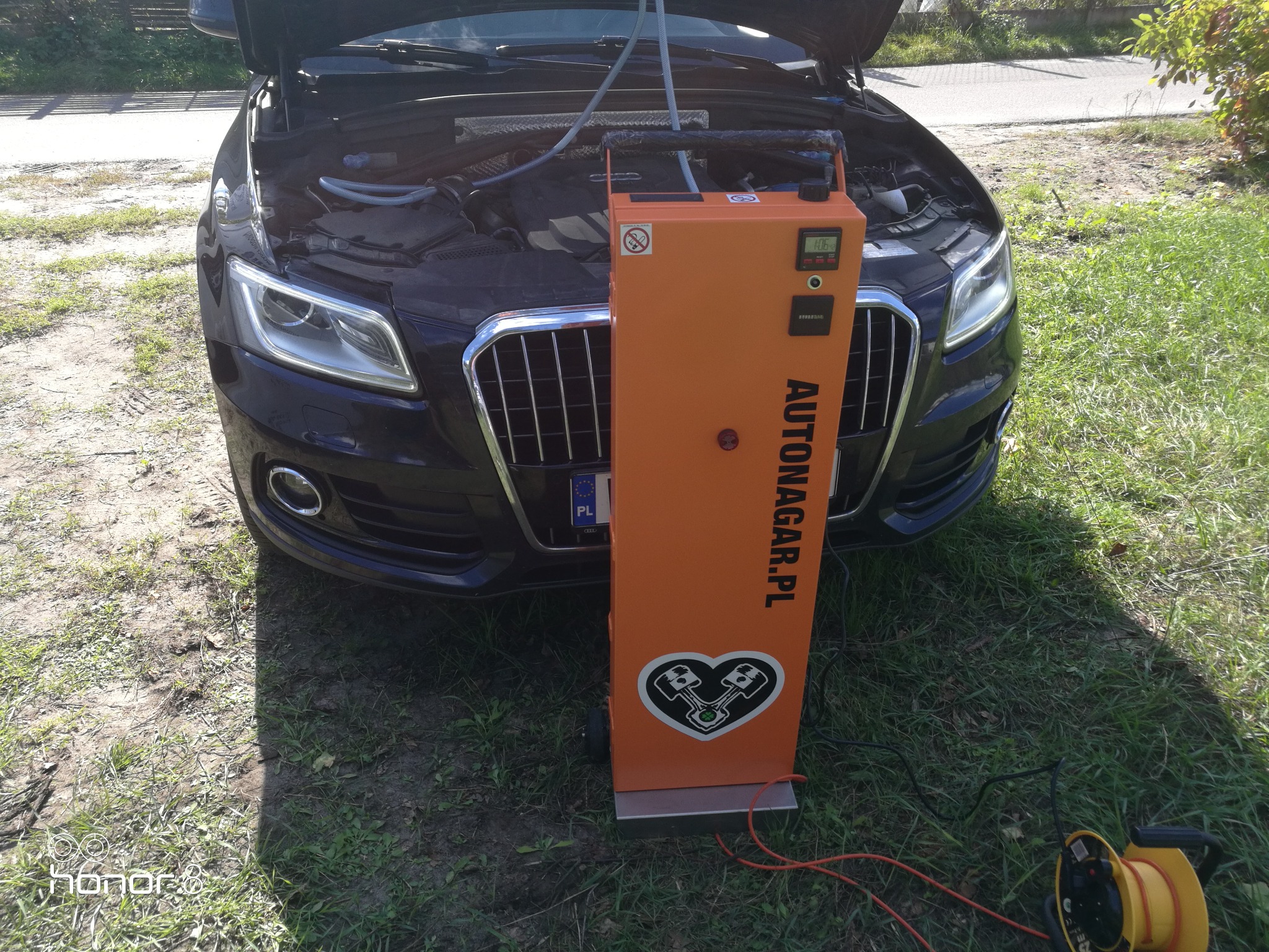 Audi Q5 z otwartą maską podczas wodorowania silnika urządzeniem Autonagar.pl na trawniku.