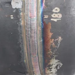 Spoina na rurze stalowej, widoczne tęczowe przebarwienia termiczne i numer 180.
