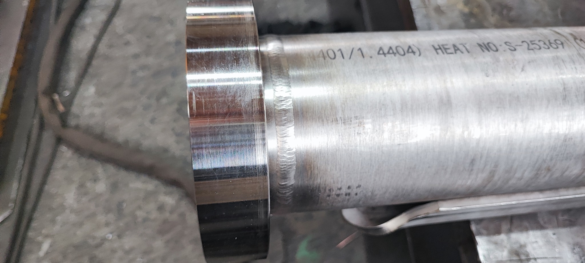 Spoina obwodowa rury ze stali nierdzewnej z widocznym oznaczeniem materiału i numerem seryjnym.