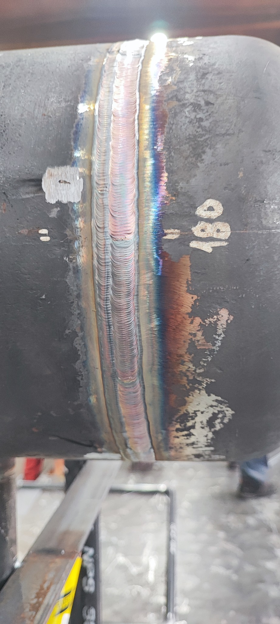 Spoina na rurze stalowej, widoczne tęczowe przebarwienia termiczne i numer 180.